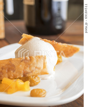 The ball of white vanilla ice cream with 2 waffles and mango fruit embellished with few raisins. 69184511