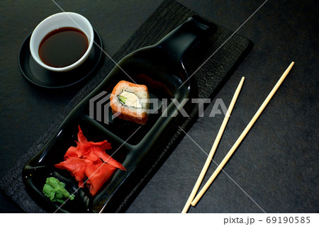The original idea of serving sushi rolls in a restaurant. Sushi roll, ginger, wasabi on a dark The original idea of serving sushi rolls in a restaurant. Sushi roll, ginger, wasabi on a dark 69190585