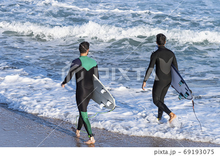 Back view of two young men with surfboards Back view of two young men with surfboards 69193075