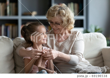 Smiling loving mature grandmother teaching little granddaughter knitting 69196538