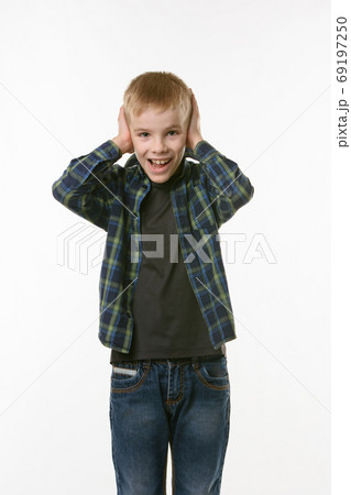 The boy covers his ears with his hands and shouts The boy covers his ears with his hands and shouts 69197250