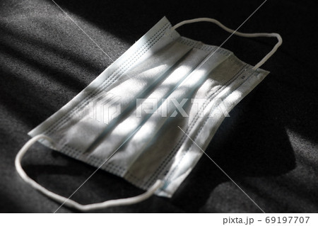 Medical mask on a dark background. Light rays hit the mask. Global fight against COVID-19 virus Medical mask on a dark background. Light rays hit the mask. Global fight against COVID-19 virus 69197707