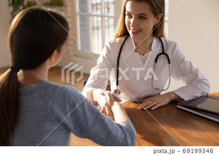 Smiling female doctor therapist shaking patient hand at meeting 69199346