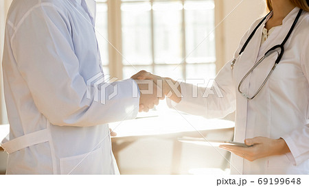 Close up two doctors colleagues shaking hands, greeting, celebrating success Close up two doctors colleagues shaking hands, greeting, celebrating success 69199648