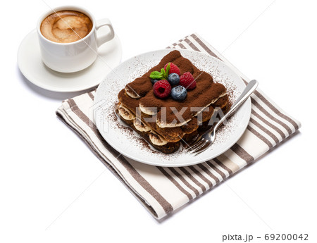portion of Classic tiramisu dessert with raspberries, blueberries and cup of fresh hot espresso isolated on white background - clipping path 69200042