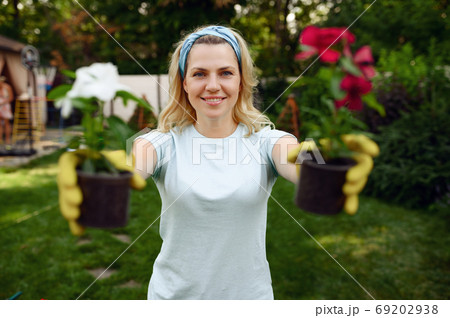 Woman shows two flowers in pots, gardening Woman shows two flowers in pots, gardening 69202938
