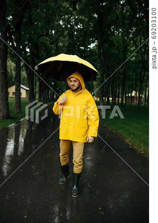 Man with umbrella walking in park in rainy day Man with umbrella walking in park in rainy day 69203100
