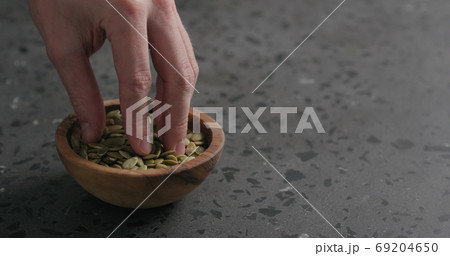 man hand takes pumpkin seeds from olive bowl with copy space man hand takes pumpkin seeds from olive bowl with copy space 69204650