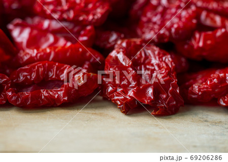 Close-up sun-dried tomatoes with spices and olive oil on wooden cutting board, background or concept Close-up sun-dried tomatoes with spices and olive oil on wooden cutting board, background or concept 69206286