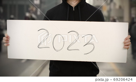 Activist wearing black holds a placard with 2023 text 69206424