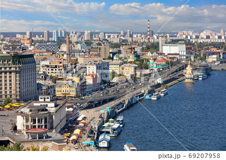The landscape of summer Kyiv with a view of the Dnipro embankment in the old Podol district, piers and pleasure boats. The landscape of summer Kyiv with a view of the Dnipro embankment in the old Podol district, piers and pleasure boats. 69207958