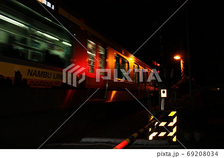 夜の暗闇の中で赤い警告灯に映し出される列車 69208034