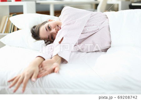 Woman lies in bed in shirt and smiles. closeup 69208742