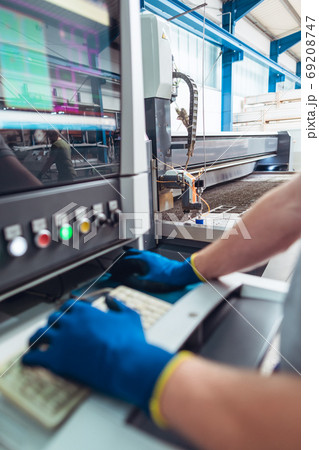 Worker operating a water jet cutting machine by pressing buttons Worker operating a water jet cutting machine by pressing buttons 69208747