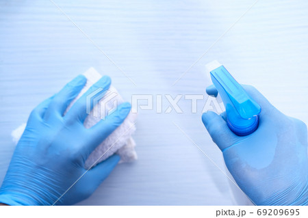 hand in disposable gloves using disinfectant spray to clean table surface, 69209695