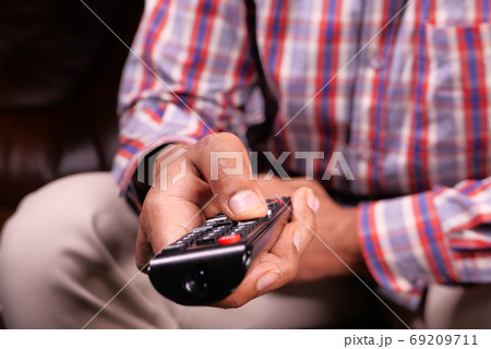 close up of man hand holding tv remote. close up of man hand holding tv remote. 69209711