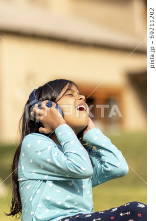 Little girl listening to music on the smartphone with her headph 69211202