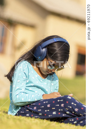 Little girl listening to music on the smartphone with her headph 69211970