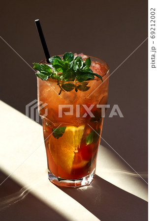 Red mojito cocktail with ice, mint leaves on paper background in selective focus, sunlight Red mojito cocktail with ice, mint leaves on paper background in selective focus, sunlight 69212002