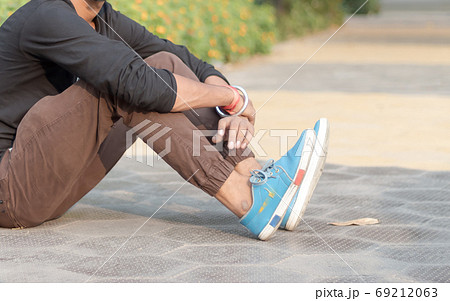 Cropped image of young sportsman, athlete man in sports clothing sitting on track and field  69212063