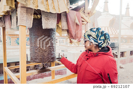 A solo traveler Indian woman in warm clothing Buddhist prayer wheel drum of a Buddhist monastery. A solo traveler Indian woman in warm clothing Buddhist prayer wheel drum of a Buddhist monastery. 69212107