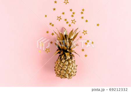 Top view golden pineapple covered golden confetti stars on pink background. Template blog social media. Minimal style. flat lay Top view golden pineapple covered golden confetti stars on pink background. Template blog social media. Minimal style. flat lay 69212332