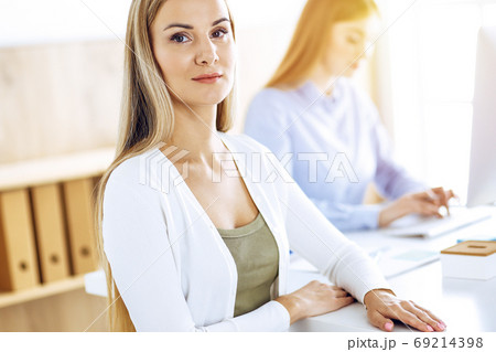 Business woman portrait at sunny office. Businesspeople or colleagues discussing something at meeting while sitting at the desk in office. Casual clothes style. Audit, tax or lawyer concept 69214398