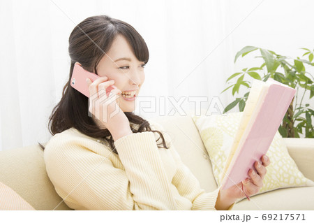 手帳を見ながら電話をする女性 69217571