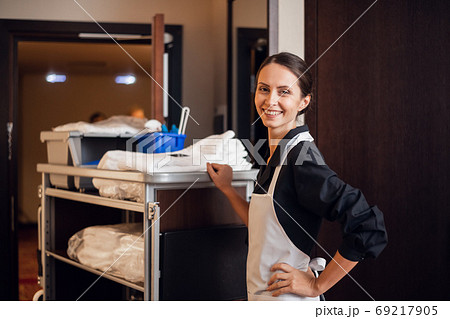 A smiling hotel maid with cleaning cart and cleaning supplies, l A smiling hotel maid with cleaning cart and cleaning supplies, l 69217905