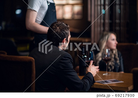 at the beginning of the date the waiter served red wine at a table for a man and a woman 69217930