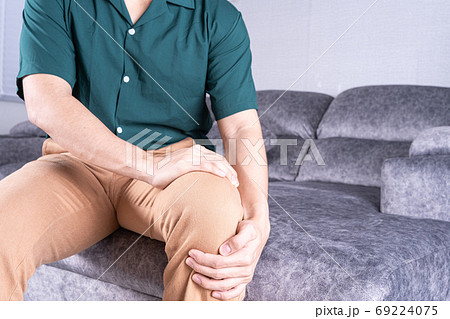 man suffering from knee pain while sitting on sofa at home. Healthcare medical or daily life concept 69224075