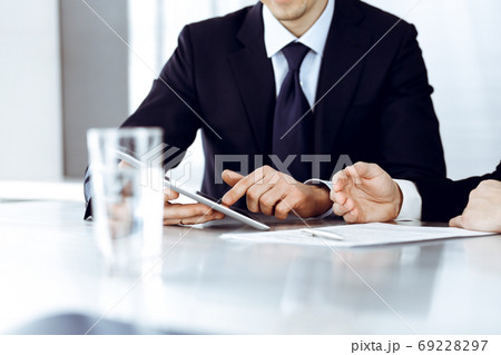 Business people using tablet computer while working together in modern office. Unknown businessman with colleague at workplace. Teamwork and partnership concept 69228297