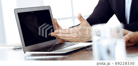 Business people using laptop computer while working together at the desk in modern office. Unknown businessman or male entrepreneur with colleague at workplace. Teamwork and partnership concept Business people using laptop computer while working together at the desk in modern office. Unknown businessman or male entrepreneur with colleague at workplace. Teamwork and partnership concept 69228330