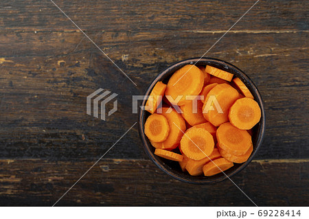 Sliced carrots in a bowl on a wooden background. Vegetable, ingr 69228414