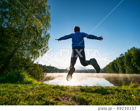 Jumping short hair boy at mountain lake makes fun 69230137