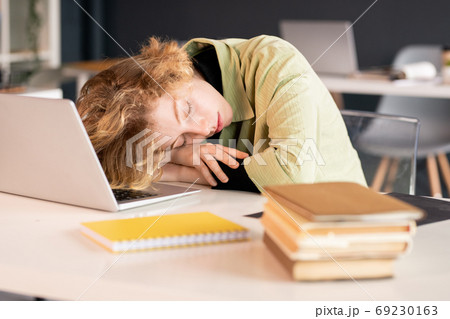 Young exhausted female student or office manager keeping head on hands Young exhausted female student or office manager keeping head on hands 69230163