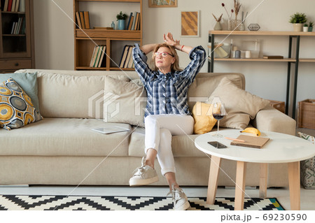 Contemporary relaxed mature woman in white jeans, sneakers and checkered shirt Contemporary relaxed mature woman in white jeans, sneakers and checkered shirt 69230590