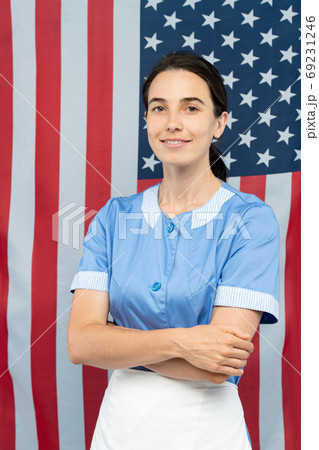 Young cheerful pretty chambermaid in blue uniform crossing arms by chest 69231246