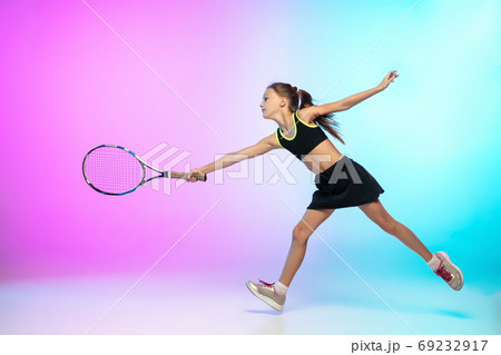Little tennis girl in black sportwear isolated on gradient background in neon light 69232917
