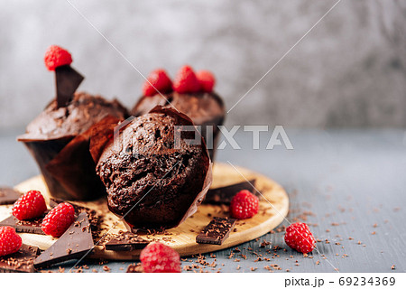 chocolate cupcakes with raspberries and bitter chocolate close-up on a light background chocolate cupcakes with raspberries and bitter chocolate close-up on a light background 69234369