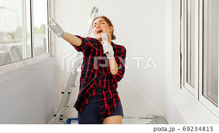 positive lady sings using brush as microphone on terrace 69234815