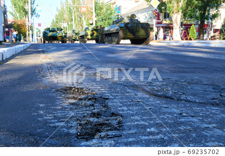 asphalt damage during military parade in the city, ordered military equipment, tanks, guns and other weapons in the street for celebration 69235702