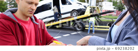 Man and woman fill out paperwork after car accident. Man and woman fill out paperwork after car accident. 69238202