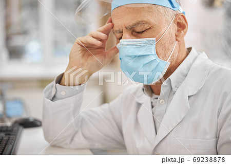 Tired senior doctor sitting with his eyes closed 69238878