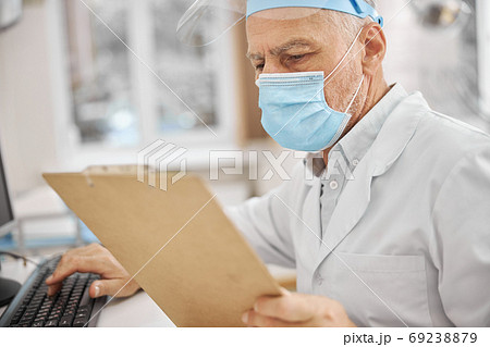 Focused medic wearing a mask and checking his clipboard 69238879