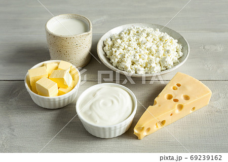 Most common dairy products are butter, cheese, milk, sour cream, cottage cheese in white dish on a white wooden background close up. Natural, organic food. 69239162