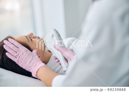 Woman receiving an ultrasound facial in a beauty salon Woman receiving an ultrasound facial in a beauty salon 69239888