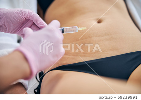 Dermatologist injecting a medication to a patient Dermatologist injecting a medication to a patient 69239991