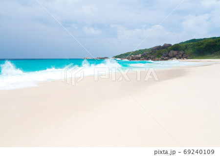 White sand beach with waves and hills with green plants White sand beach with waves and hills with green plants 69240109