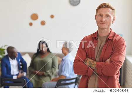 Tattooed Man Posing against Group Discussion Tattooed Man Posing against Group Discussion 69240343